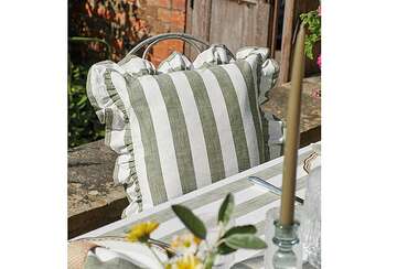 Soft Green Stripe Ruffle Cushion placed on a garden chair