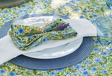 Cornflower Blue placemat on a dinner table with fleur napkins and tablecloth