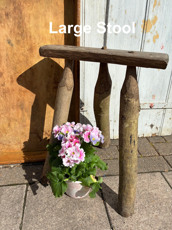 Handmade wooden bodger stool with rustic finish, featuring sturdy legs and decorative floral arrangement.