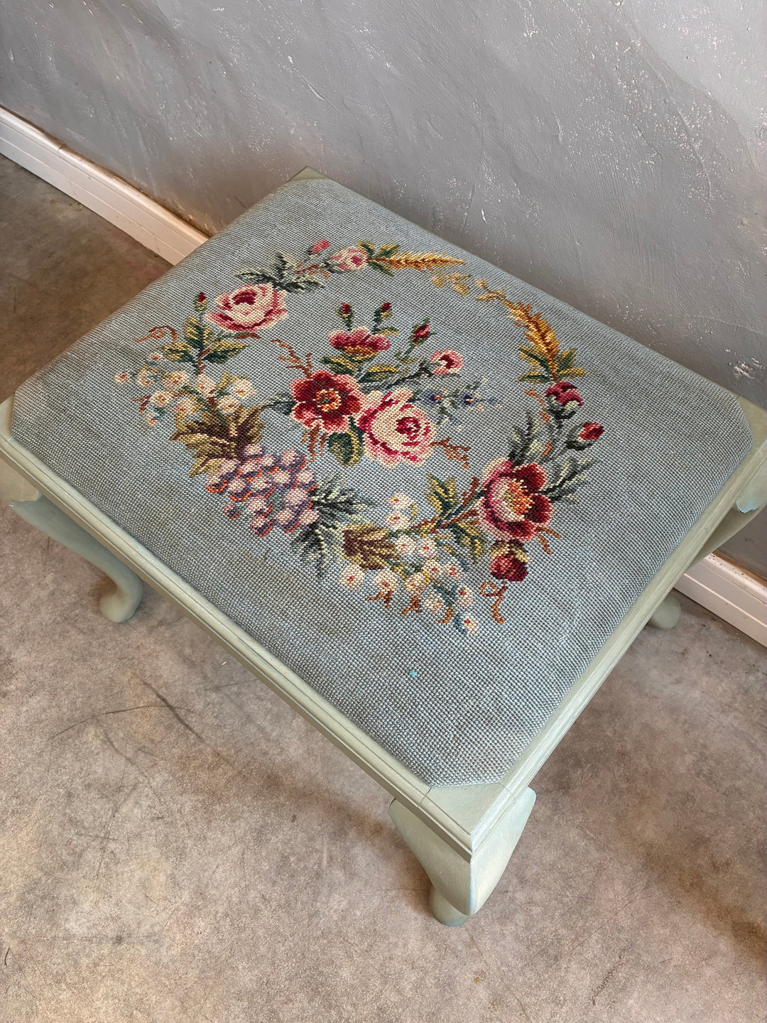 Vintage Stool with Floral Cushion featuring a floral needlepoint design on a blue background.