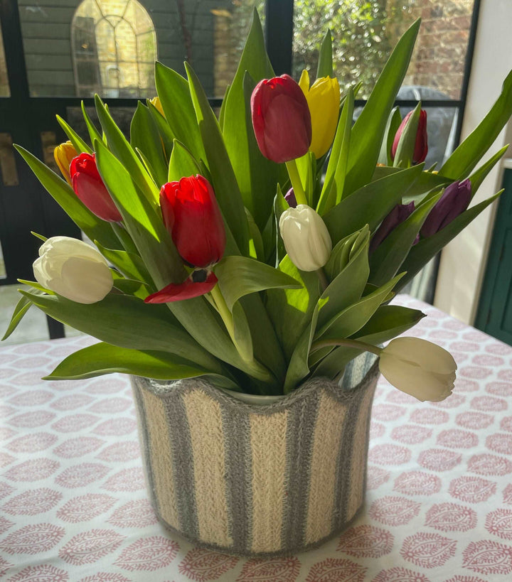 blue and white strip tulip shaped basket  filled with fresh tulips in jug