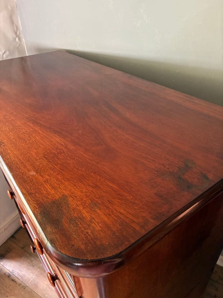 Elegant mahogany surface of a large Victorian chest of drawers featuring smooth finish and rich color.