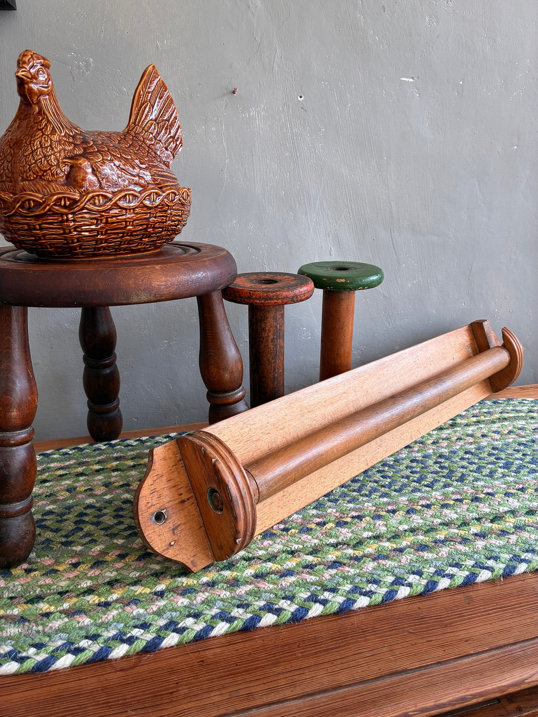 Vintage French wooden towel holder displayed with rustic decor on a woven mat, perfect for kitchen or bathroom.