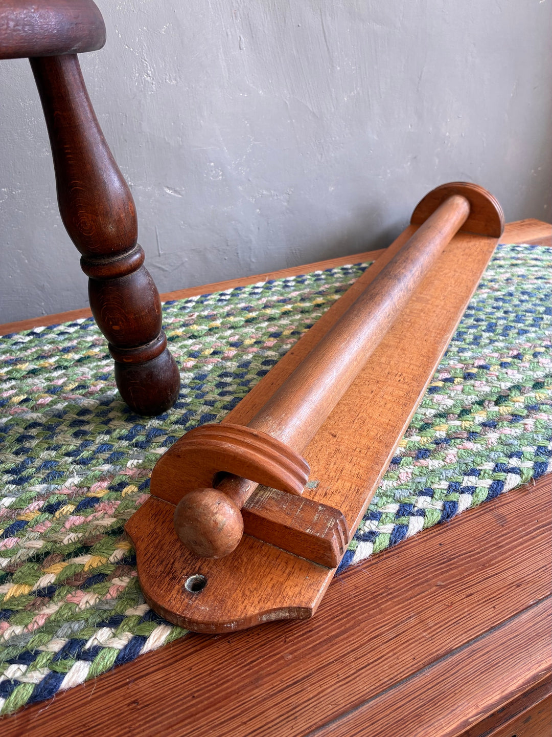 Vintage French wooden towel holder on a woven mat, showcasing rustic charm for kitchen or bathroom use.