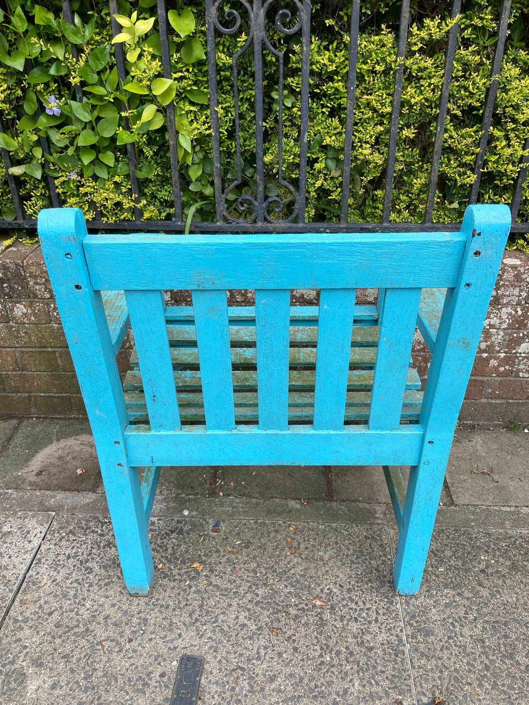 rear view of blue wooden chair in front of garden wall