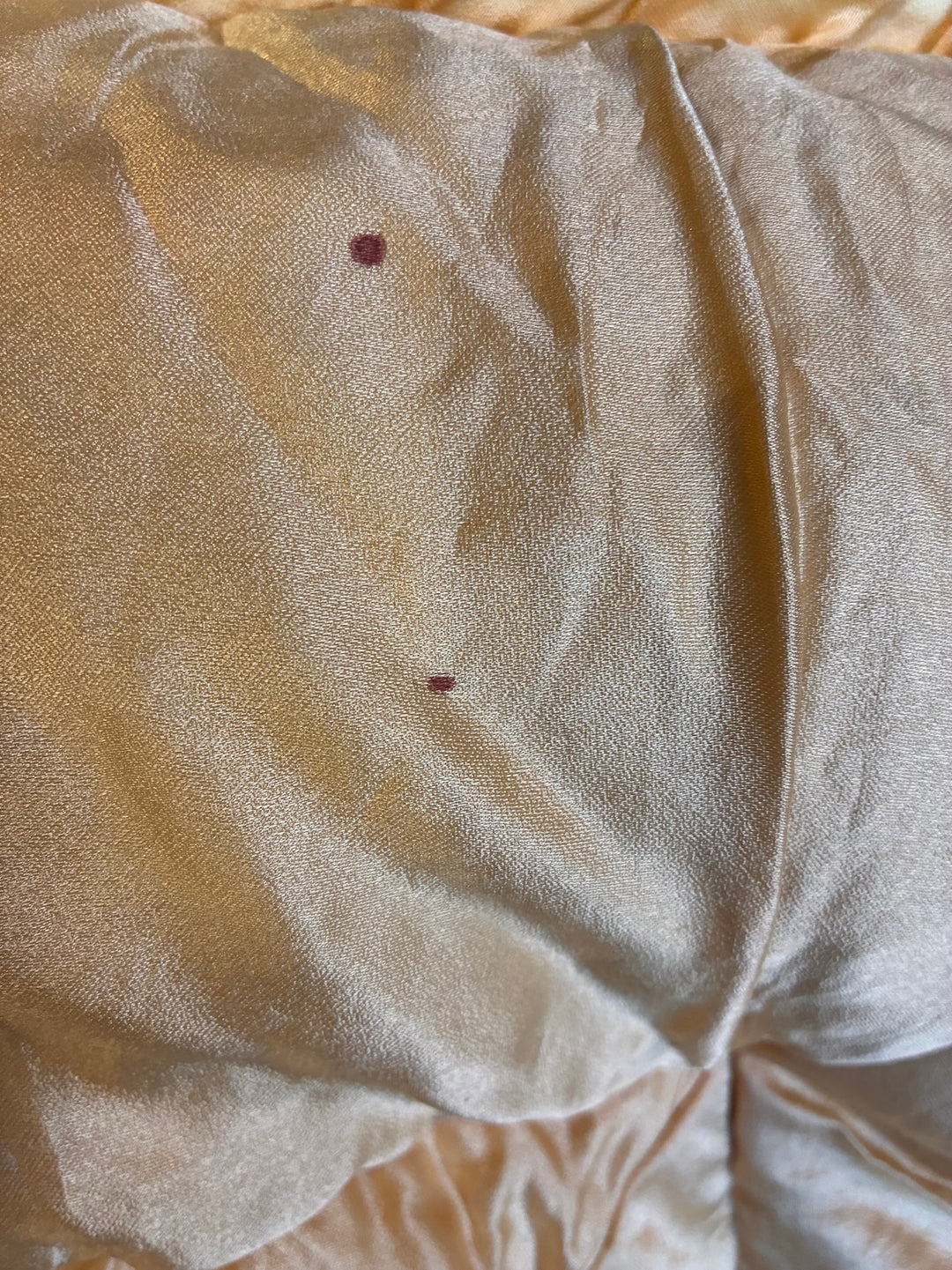 Close-up of vintage 1930s single eiderdown showing satin fabric with a small stain.
