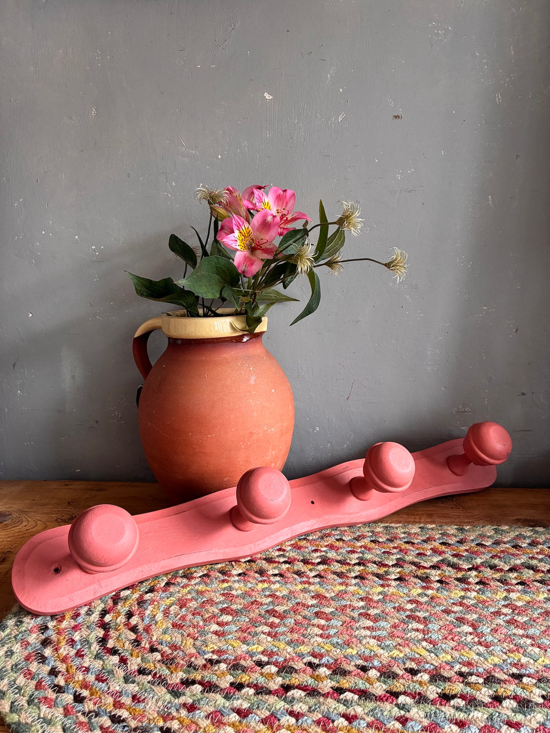 Earthy Pink Vintage French Coat Hooks paired with a terracotta vase and flowers on a handmade rug.