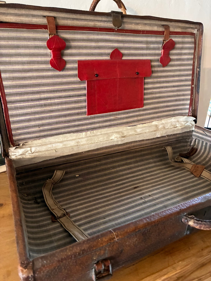 Interior view of Vintage French Leather Suitcase showcasing red leather pocket and ticking-striped lining.