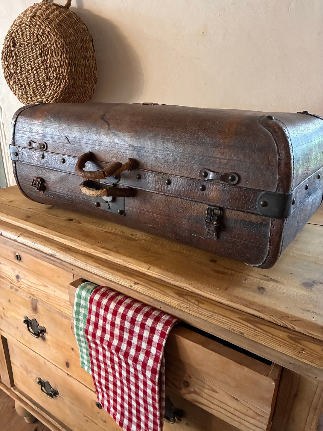 Vintage French Leather Suitcase on a wooden dresser with a checkered cloth.