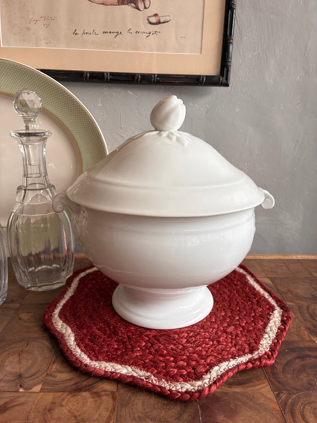 Vintage White Porcelain French Tureen elegantly displayed on a rustic table with a red woven mat.