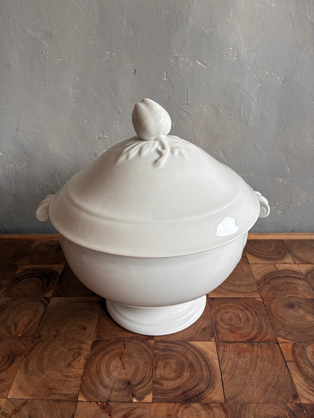 Vintage White Porcelain French Tureen with intricate lid on wooden surface.