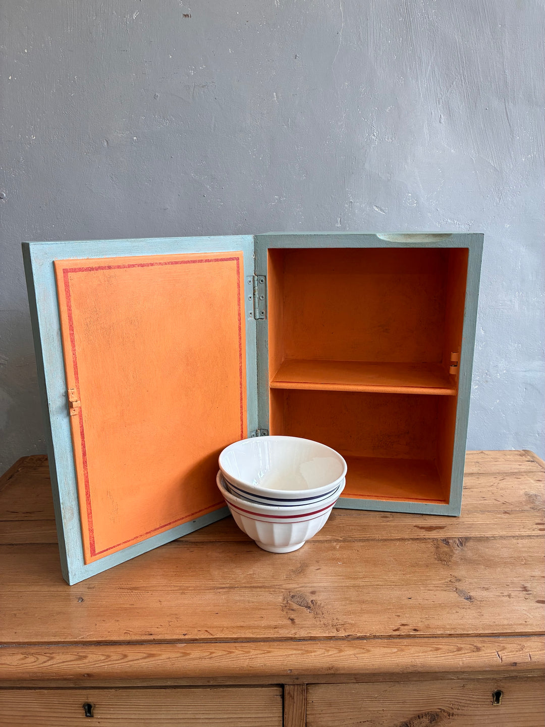 Vintage mirrored wall cabinet in soft blue with orange interior, perfect for rustic storage - Source for the Goose, Devon.