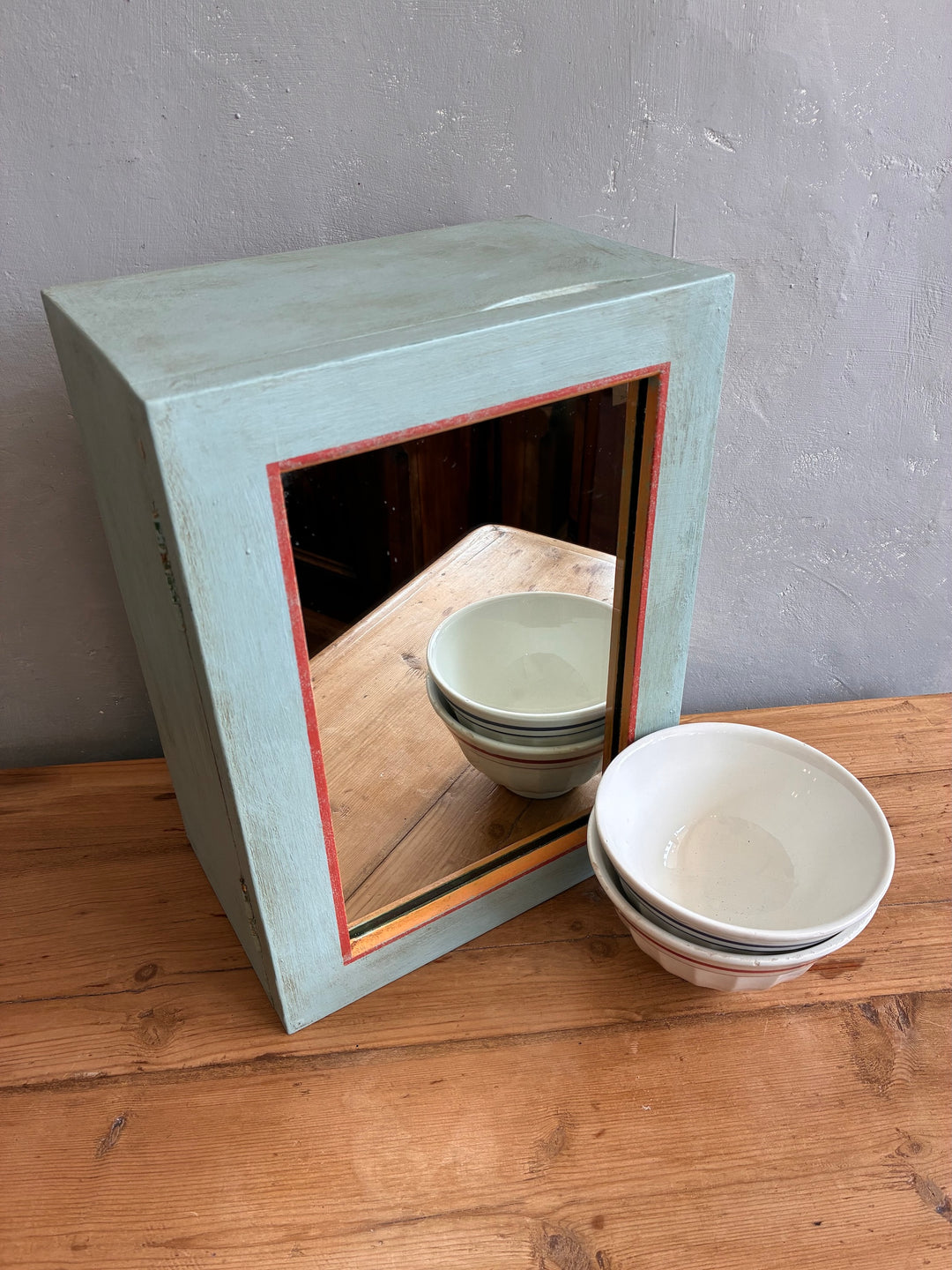 Vintage mirrored wall cabinet in soft blue with colorful bowls, perfect for quirky storage, by Source for the Goose, Devon.