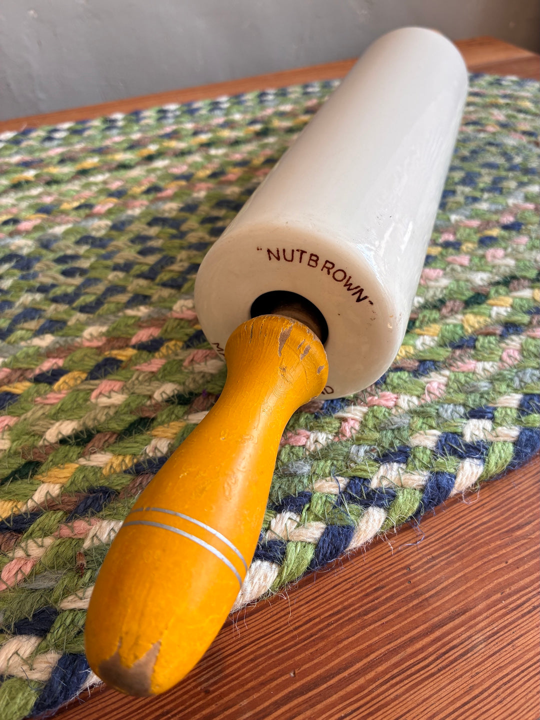 Vintage Nutbrown rolling pin with yellow handles on a woven mat, sourced from Source for the Goose, Devon.