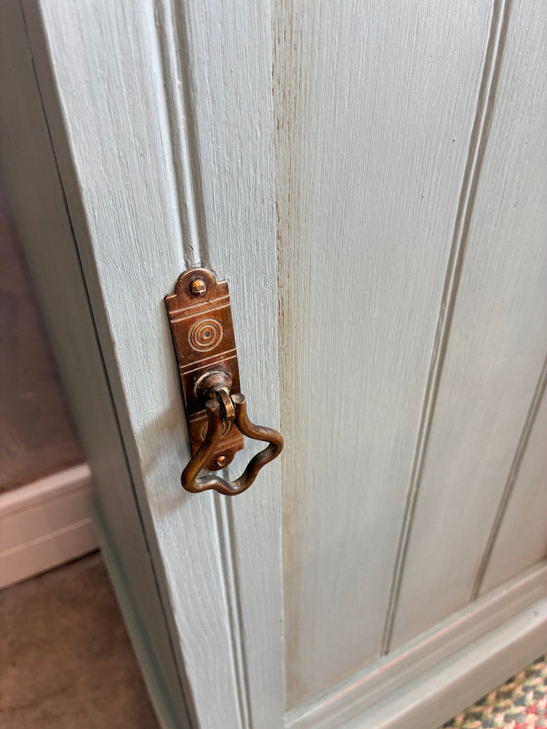 Close-up of vintage brass handle on a duck egg blue cupboard, showcasing rustic charm and detailed craftsmanship.
