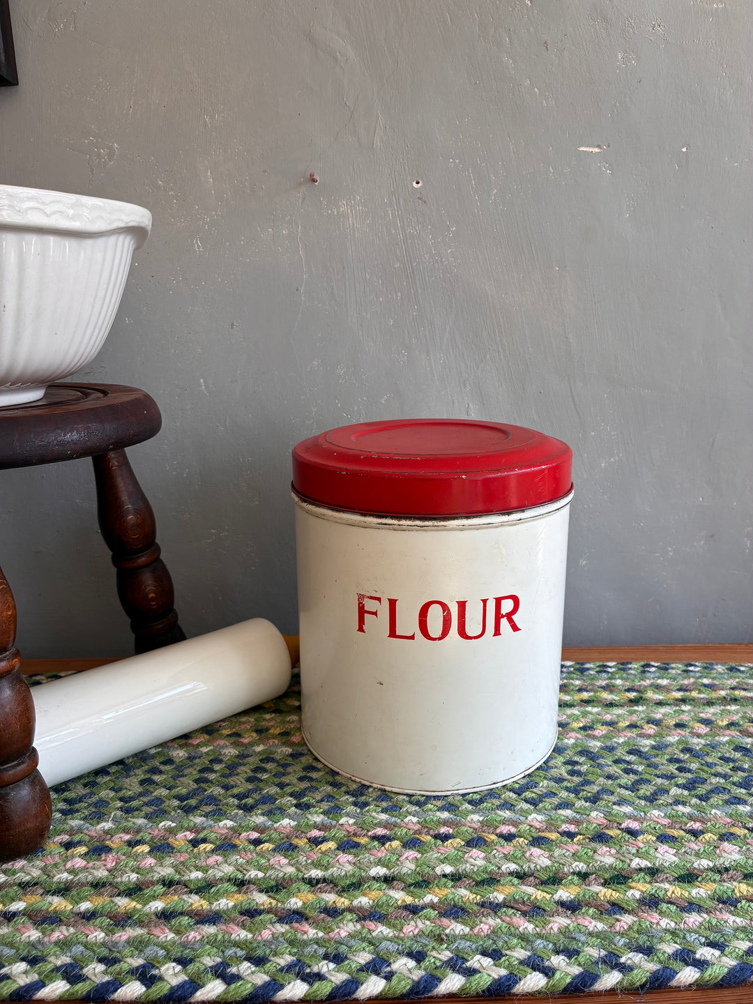 Vintage red and white Tala flour bin on an antique dresser, perfect for adding retro charm to your kitchen.