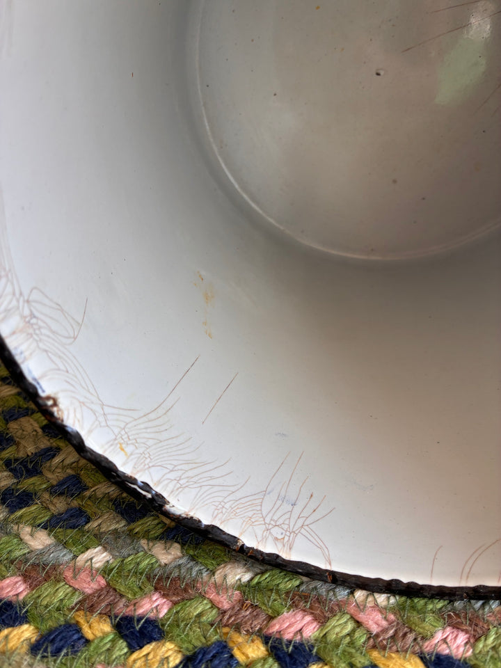 Inside view of a vintage white bowl with hairline cracks on colorful woven surface.
