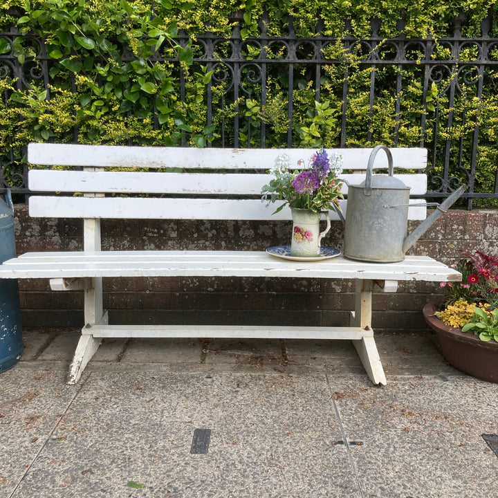 curved white Vintage Wooden Garden Bench with old watering can and flowers