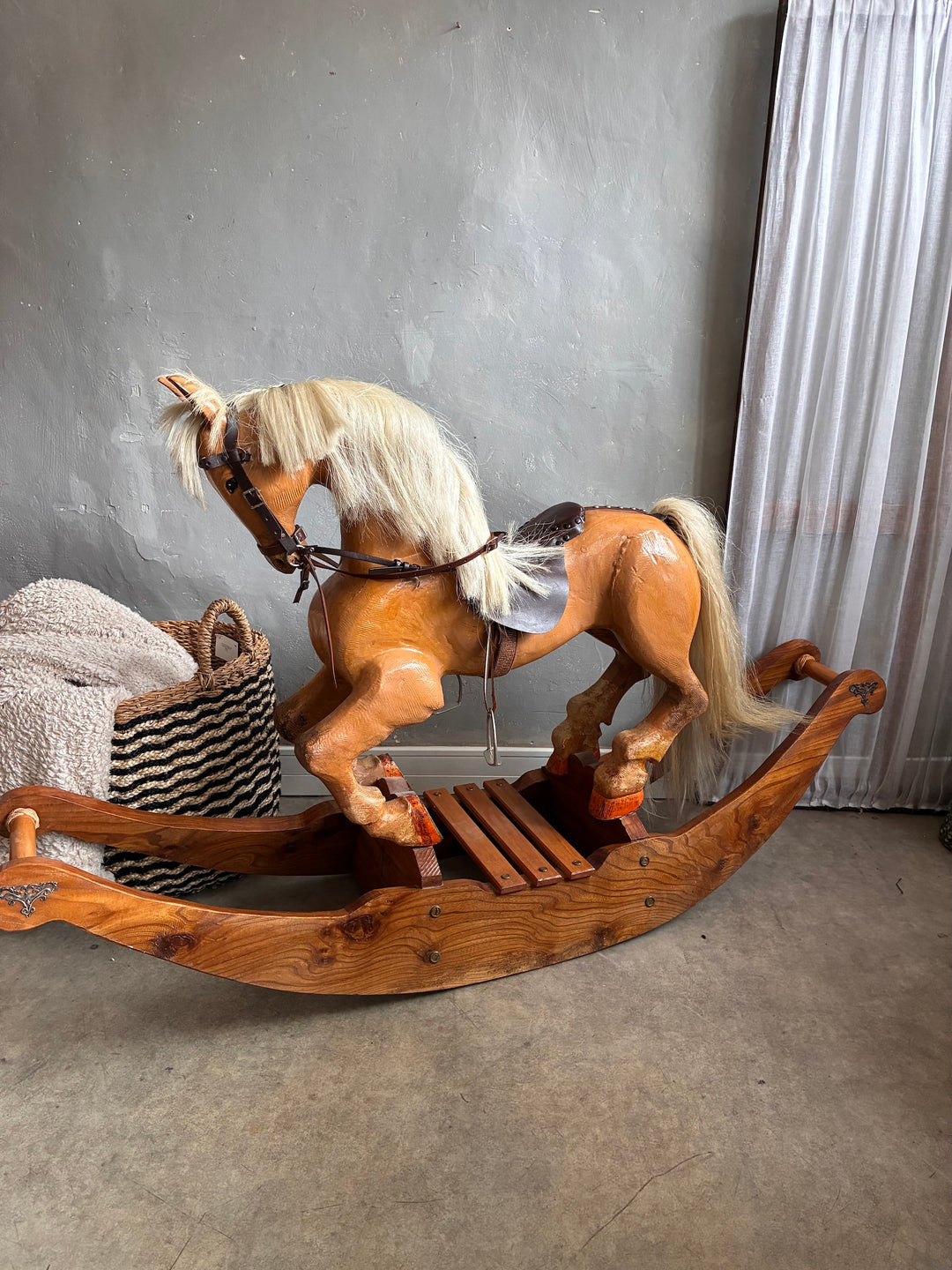 Vintage Wooden Rocking Horse displayed in a room with a neutral backdrop and cozy basket nearby.