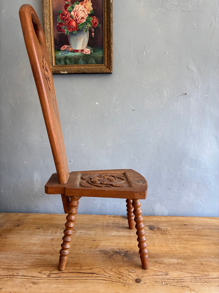 Vintage Spinning Chair with carved light oak seat and heart-shaped backrest against a grey wall.