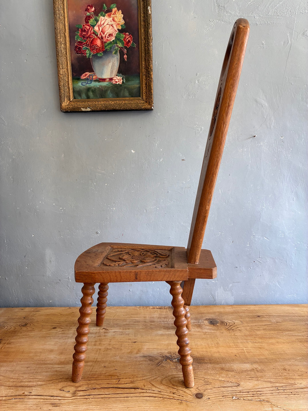 Side view of a Vintage Spinning Chair with carved light oak seat and unique backrest design.