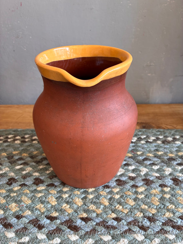 Vintage Terracotta Jug - Yellow Glaze Rim displayed on a woven rug, showcasing rustic charm and unique craftsmanship.