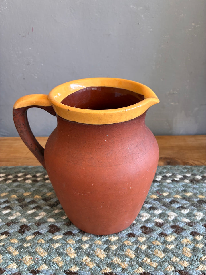 Vintage Terracotta Jug - Yellow Glaze Rim on a textured mat, showcasing its rustic charm and traditional Devonware style.