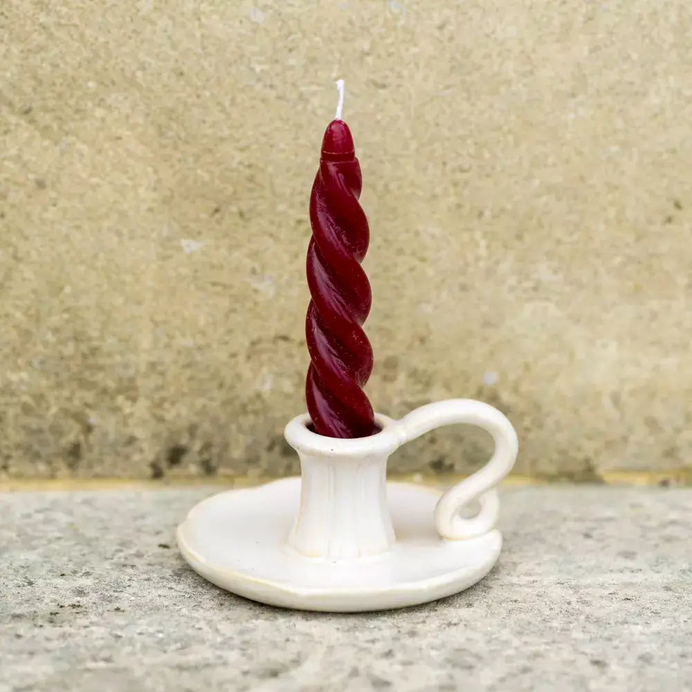 Vintage style white ceramic candle holder with a twisted red candle, perfect for home decor enhancement.