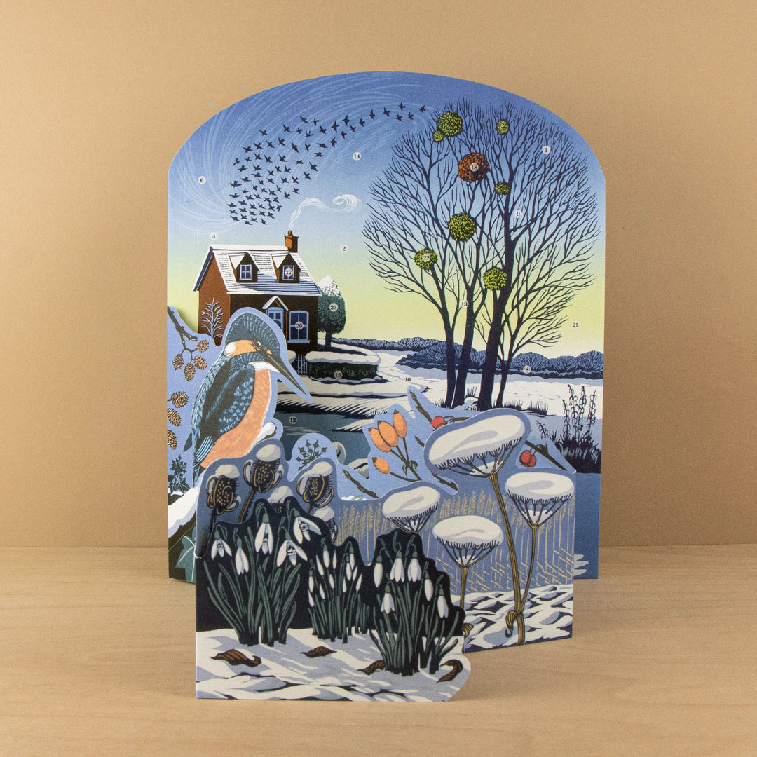 Winter Riverside Advent 2026 Calendar - Niki Bowers featuring a cozy winter scene with a cottage and snow-covered landscape.