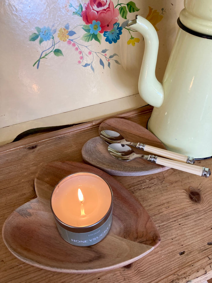 Heart shaped wooden dishes by Source for the Goose, styled with a candle and utensils on a rustic table.
