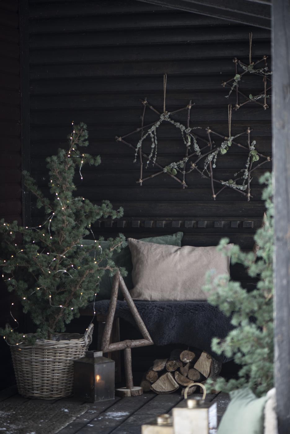 ourdoor Christmas decor featuring a tall rustic wood Christmas tree