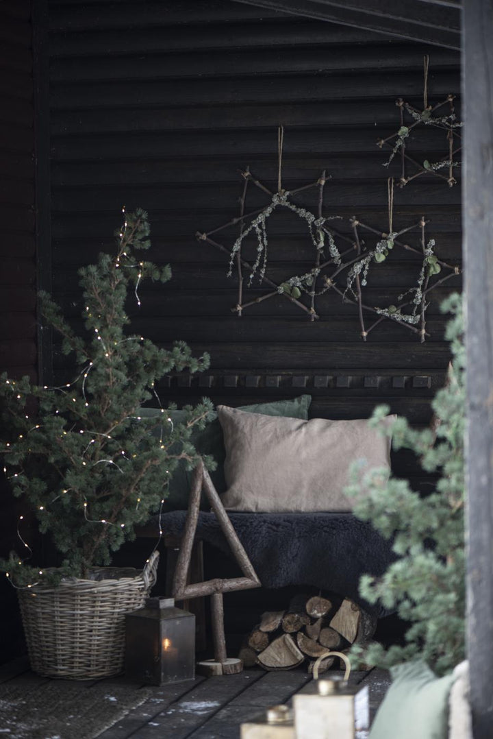 ourdoor Christmas decor featuring a tall rustic wood Christmas tree